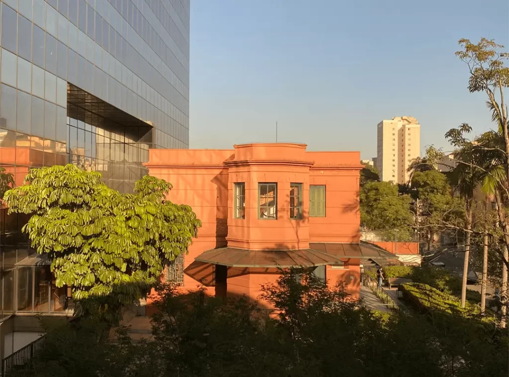 Fachada de edifício histórico restaurado em Campos Elíseos, São Paulo, cercado por árvores e com prédios modernos ao fundo, destacando a preservação do patrimônio arquitetônico.