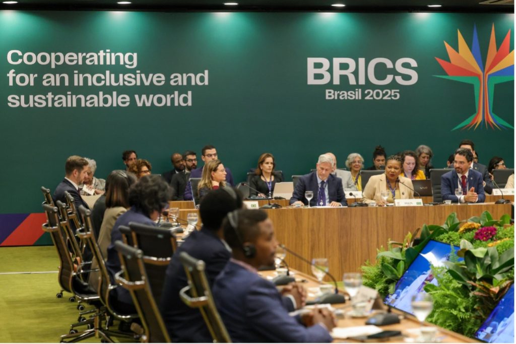 Reunião do BRICS Brasil 2025 com delegações internacionais em mesa de conferência, sob o lema “Cooperating for an inclusive and sustainable world”.